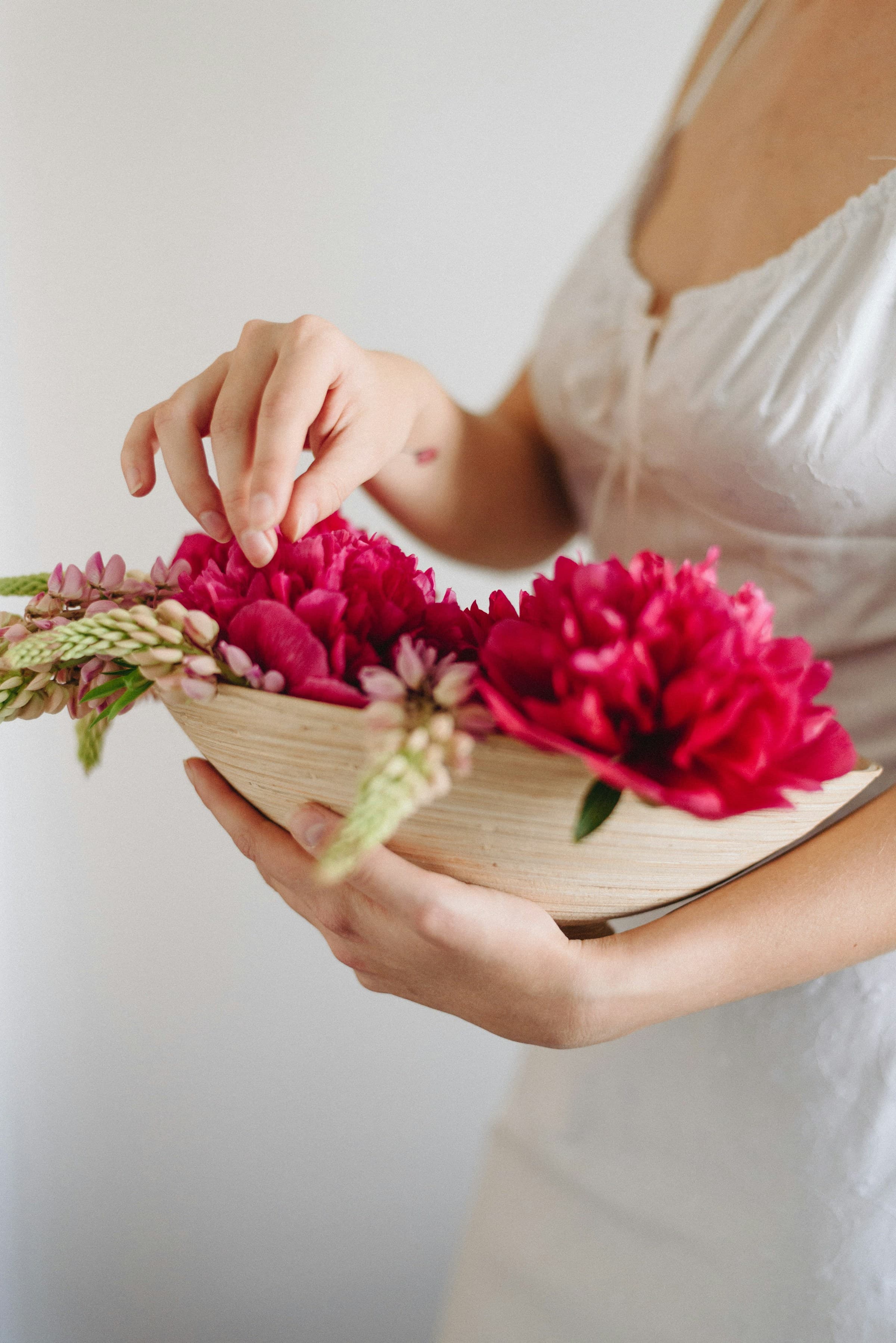 A woman carrying a basket of freshly cut garden flowers