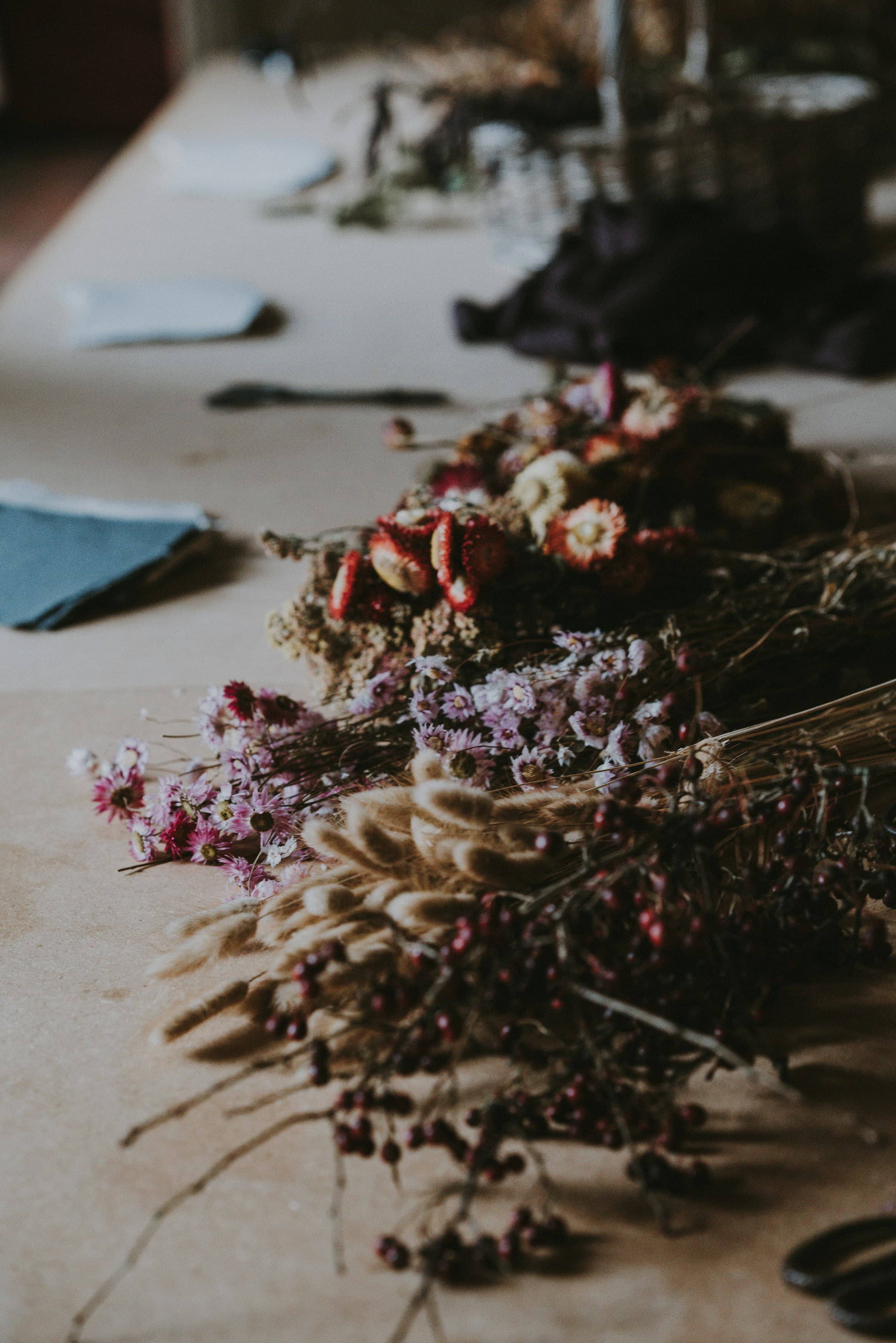 A generous bunch of dried cornflowers and grasses laid on a wooden tabletop